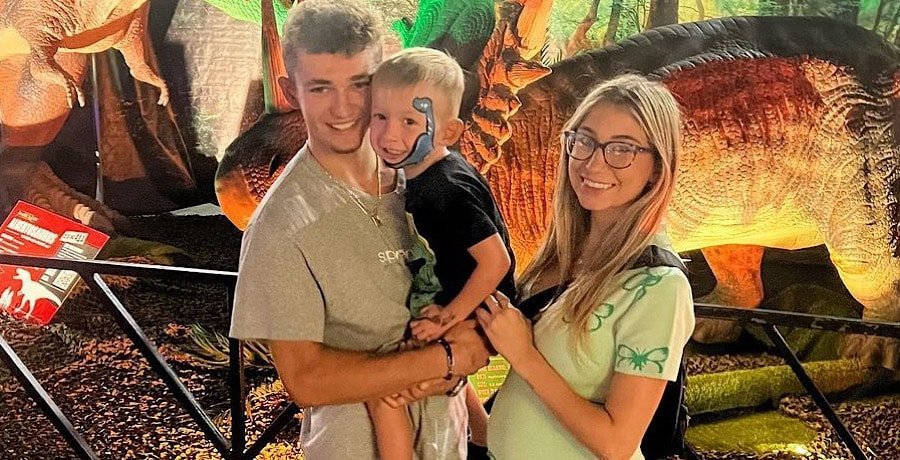 Jenna Ronan and JJ Della with their son at a dinosaur exhibit