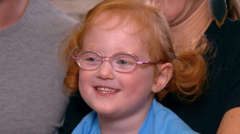 Young Hazel Busby smiling while wearing pink glasses