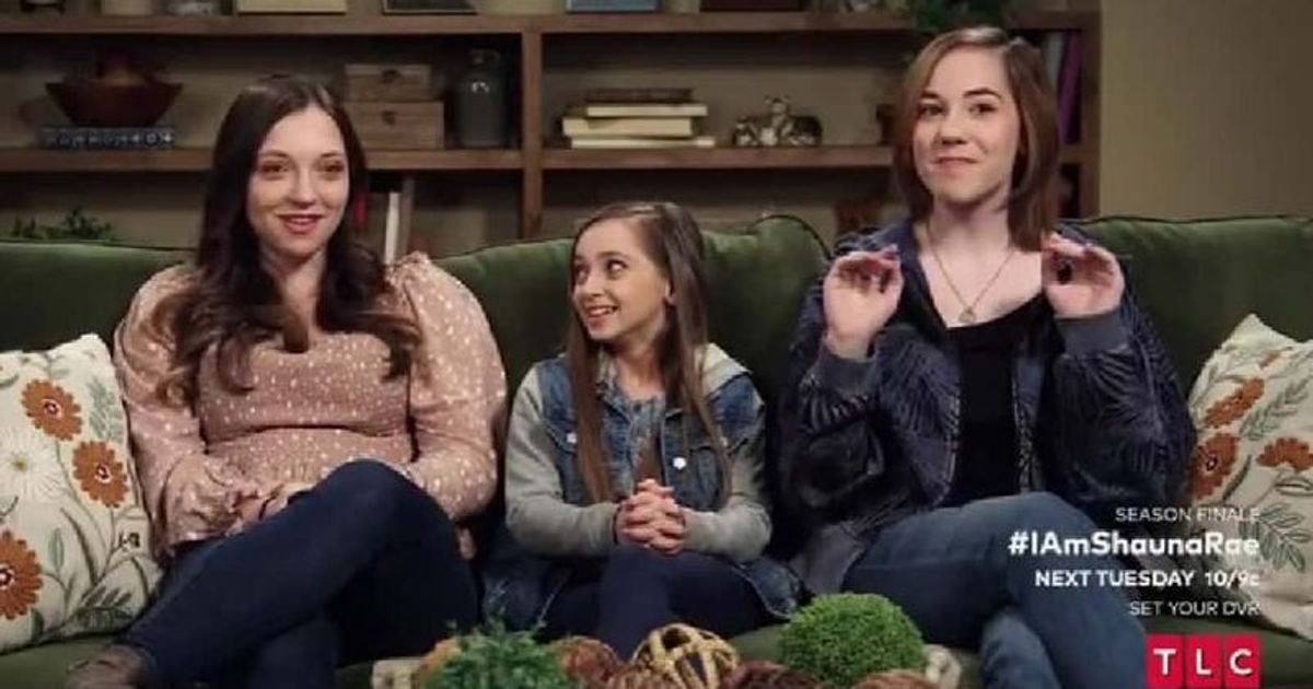 Shauna Rae sitting between her sisters on a green sofa