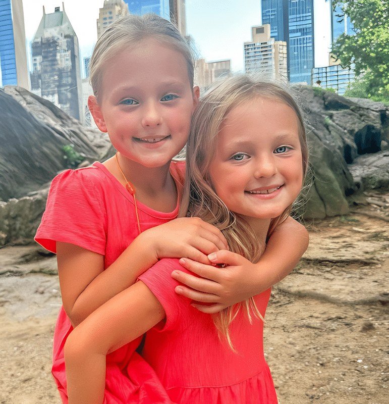 Ava and Olivia Busby hugging in matching pink outfits