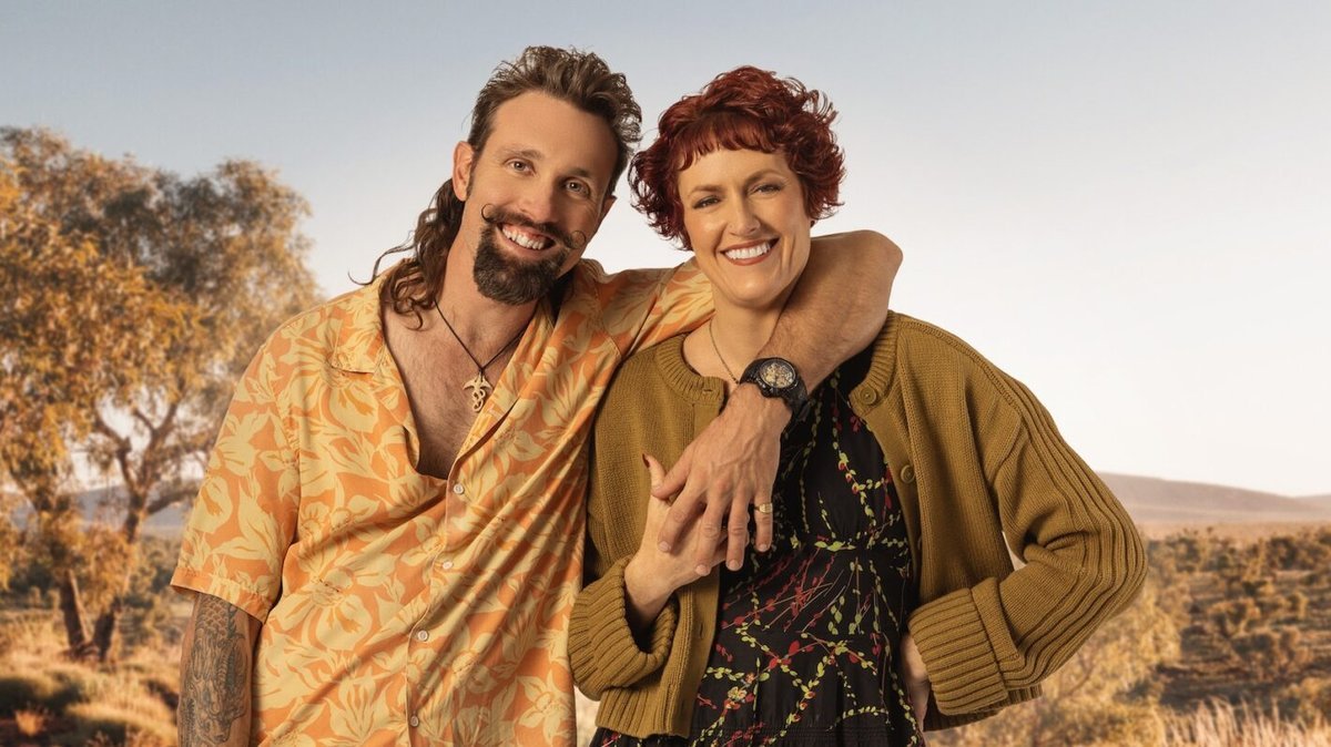 Nigel and Andi smiling together against an Australian outback backdrop