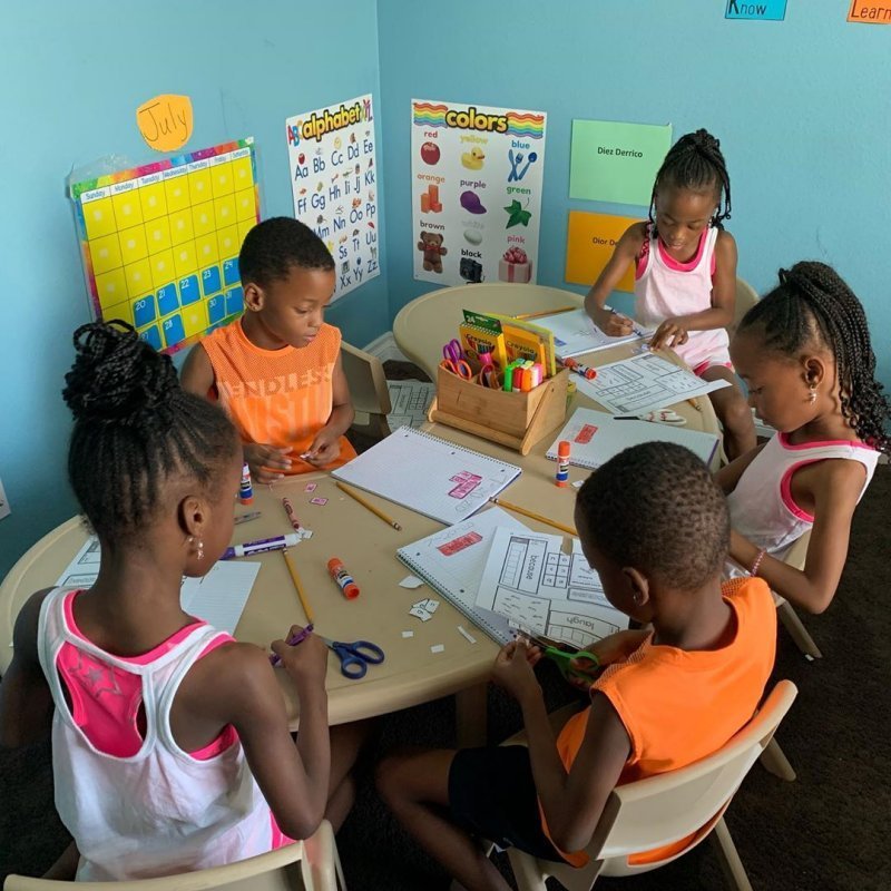 Five Derrico children doing schoolwork around a table