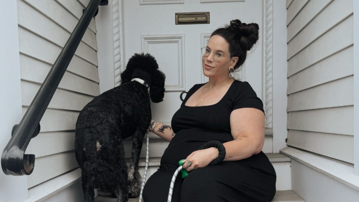 Whitney Way Thore sitting on porch steps with her black dog