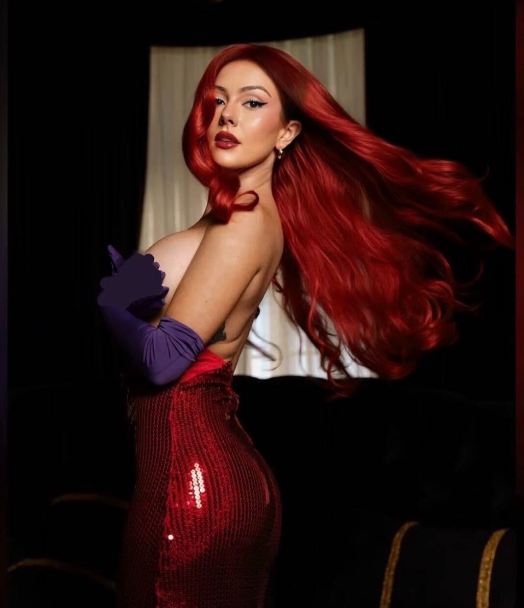 Kara Leona dressed as Jessica Rabbit, red sequin gown and long red hair