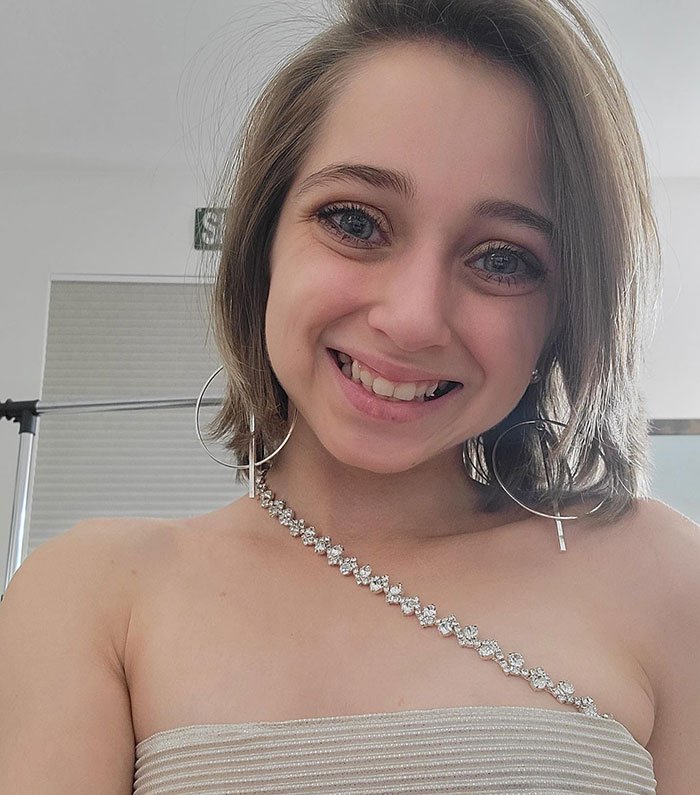 Shauna Rae smiling in a glam selfie with hoop earrings and a rhinestone strap top