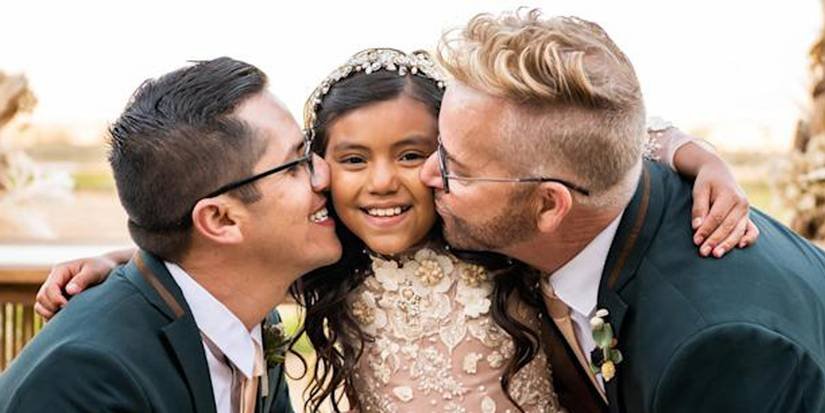 Kenny and Armando kissing their daughter Hannah on the cheeks at their wedding
