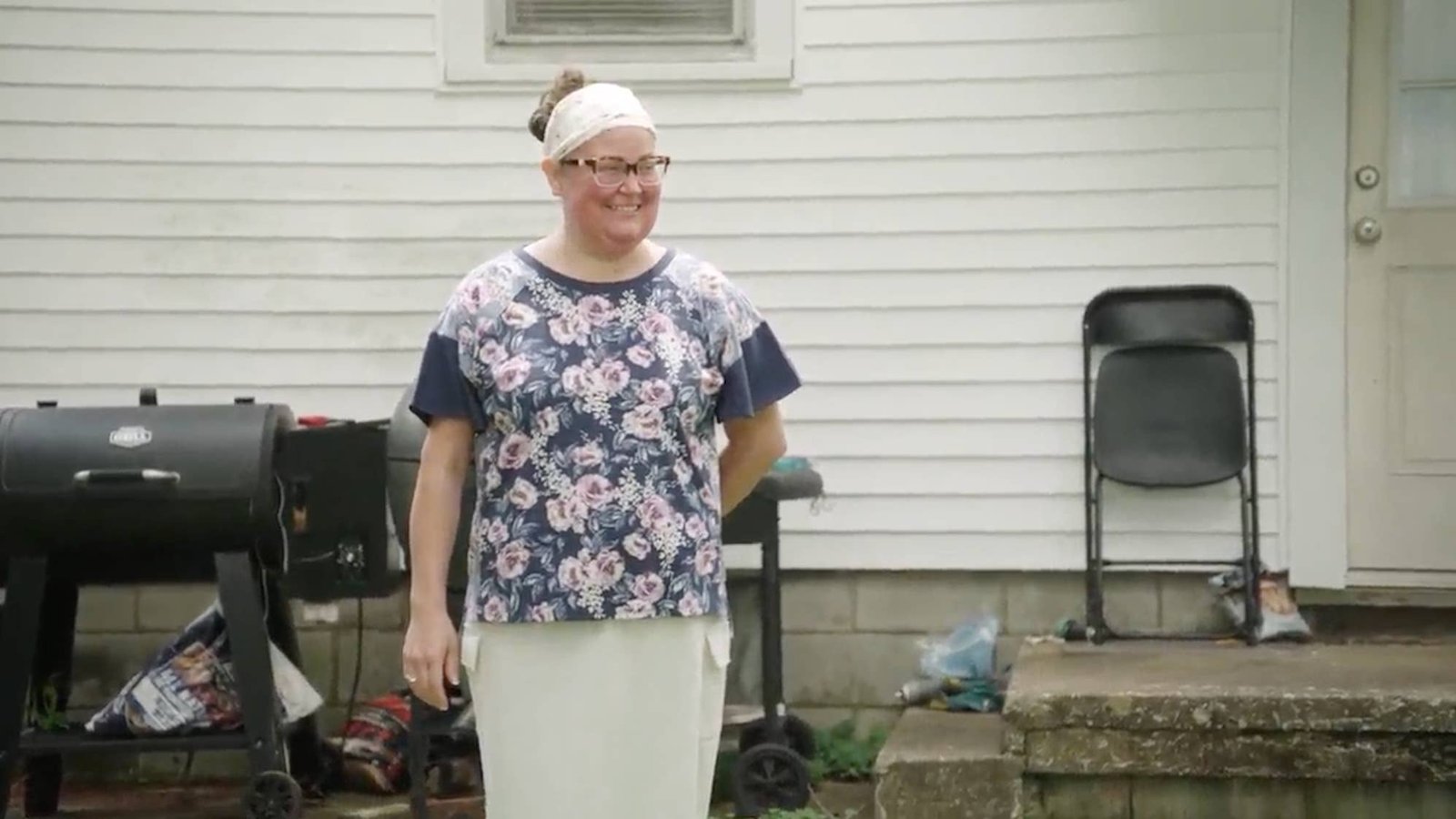 Brittany Combs smiling outdoors in a floral top and white head covering