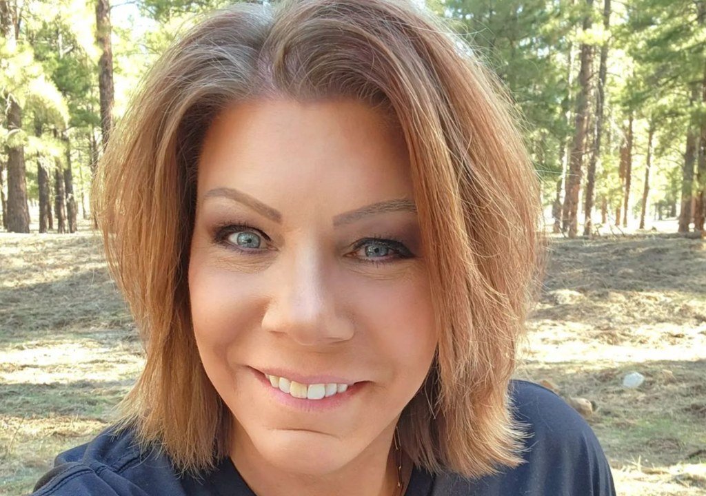 Meri Brown smiling in an outdoor selfie in the woods