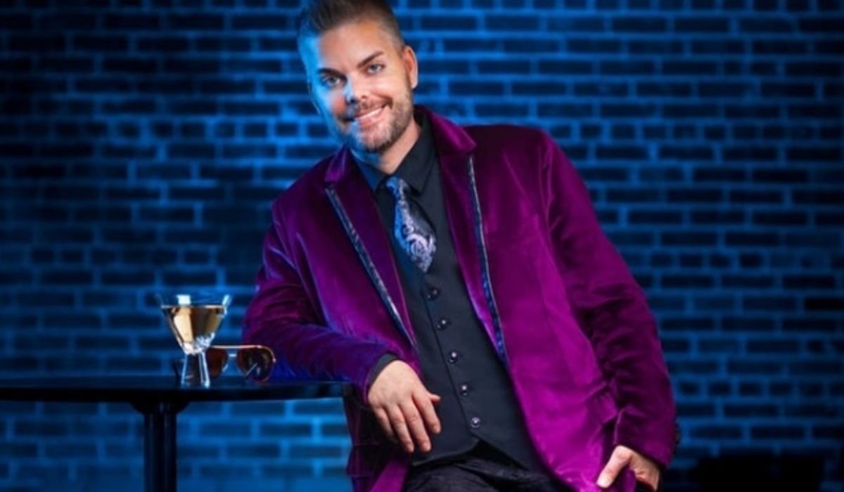 Tim Malcolm smiling in a purple velvet blazer