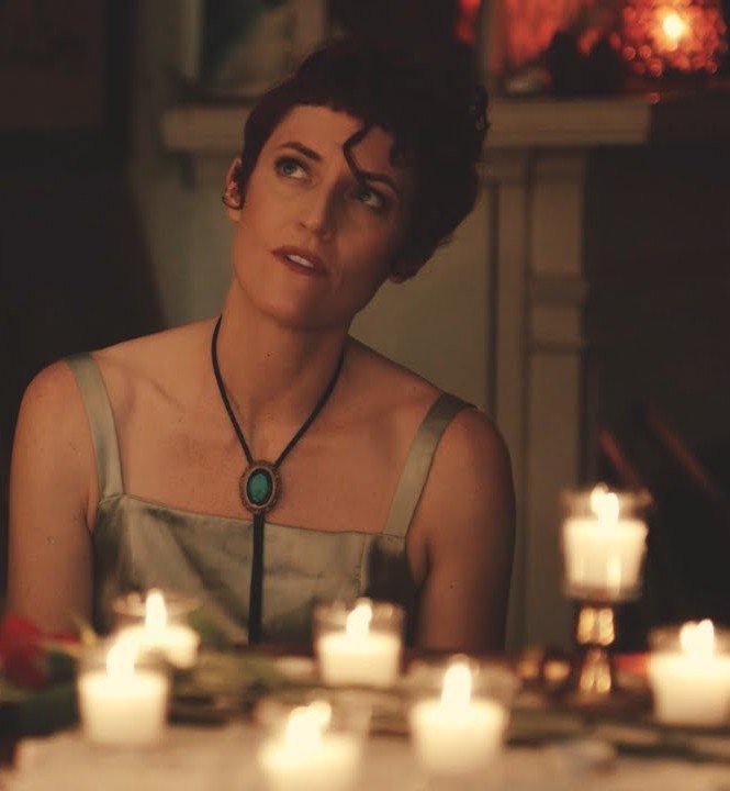 Andi Jane in a close-up by candlelight, looking emotional